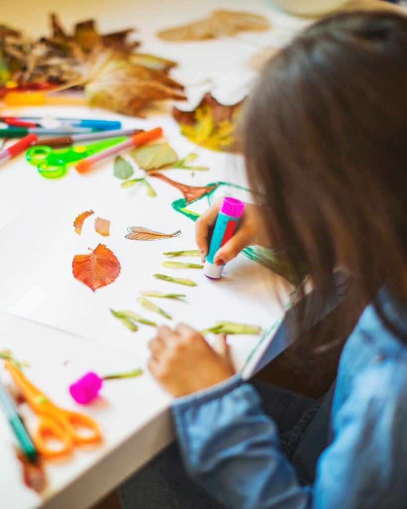 bambina che crea lavoretti con foglie d'autunno