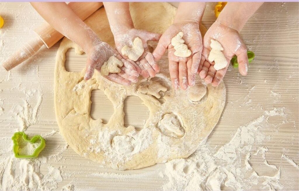 Attività sensoriale per bambini: toccare farina e impasto mentre si preparano biscotti fatti in casa